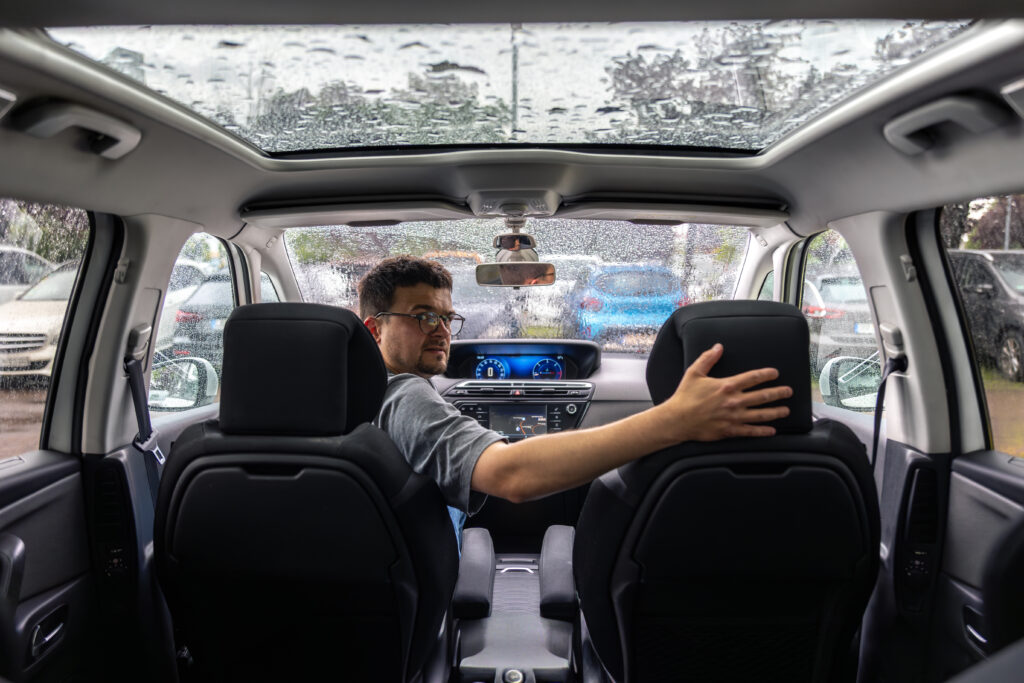 Car interior view with panoramic roof during rainy weather