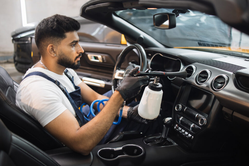 Bearded auto service worker cleaning vehicle exterior