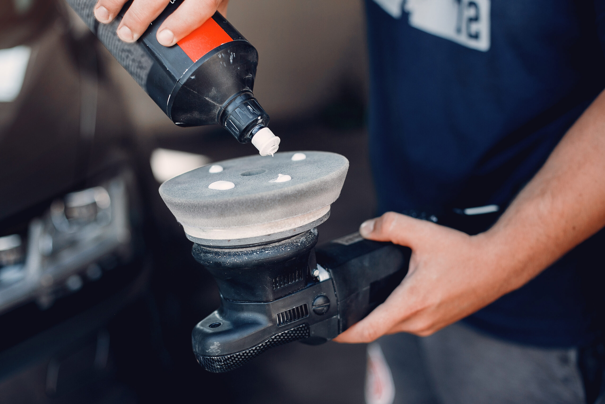 Man polishing car surface inside garage detailing area
