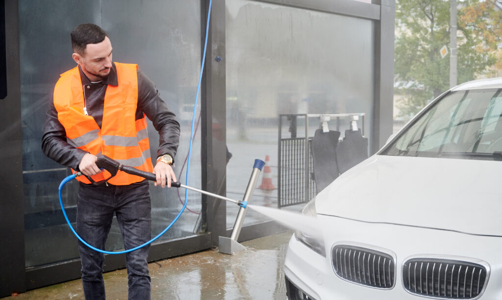 Man washing car at car wash station wearing safety vest