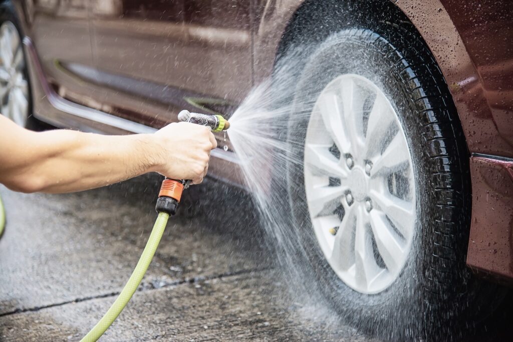 Man washing car using shampoo and flowing water
