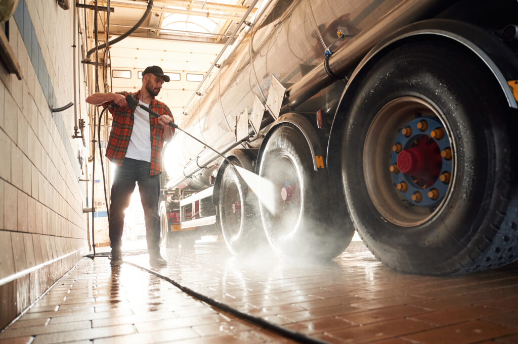 Young truck driver washing vehicle exterior outdoors