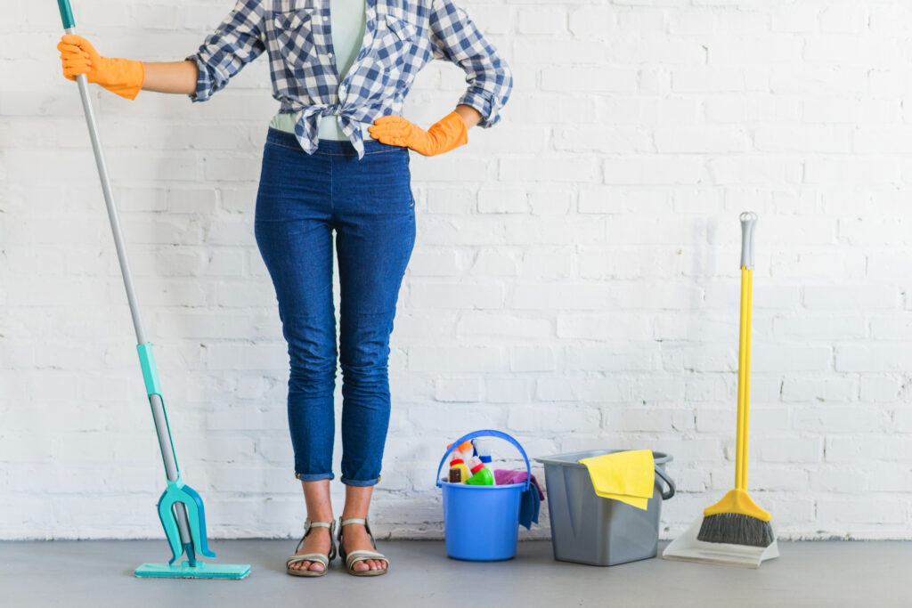Woman standing in front of brick wall holding cleaning equipment